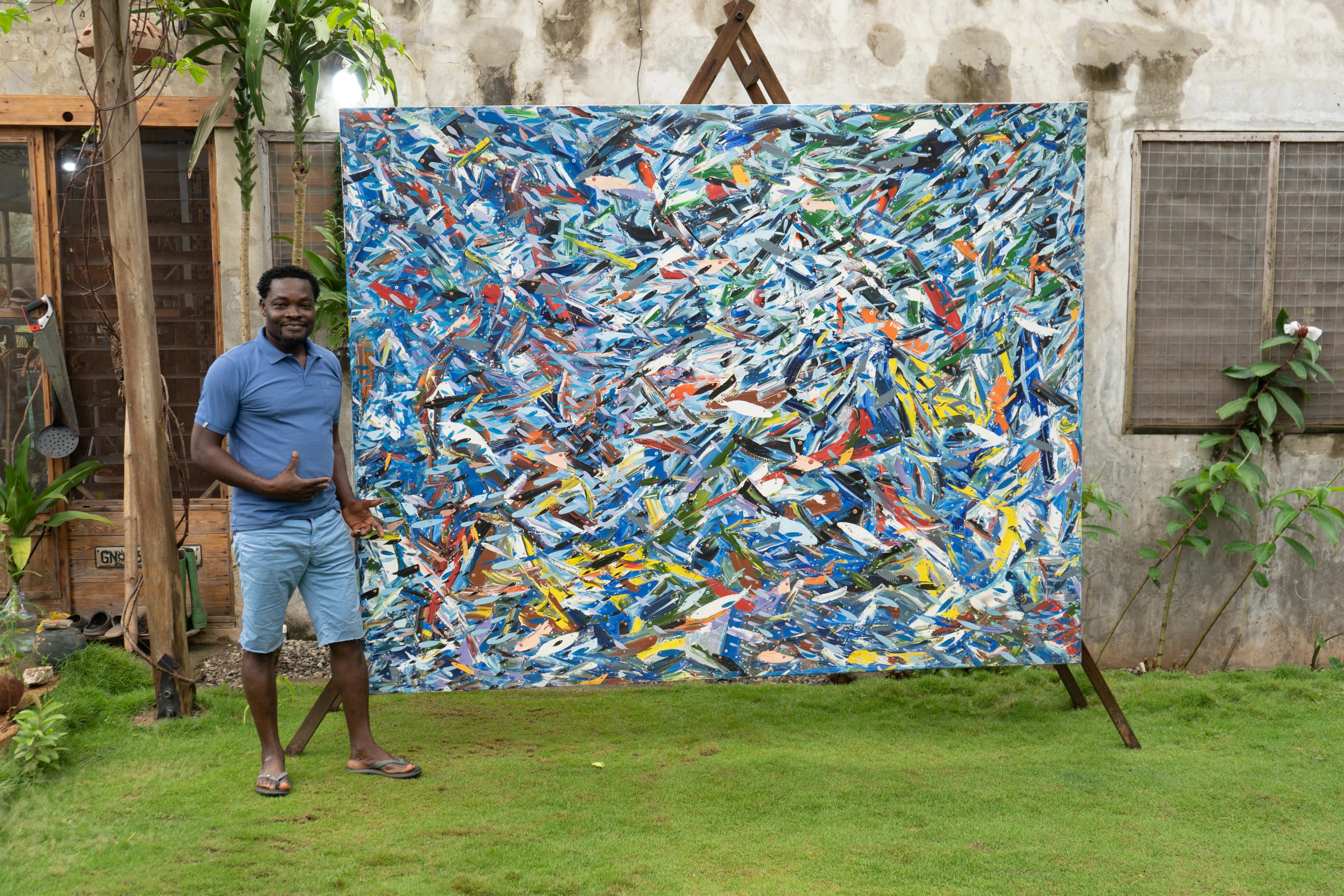Kobina Nyarko beside one of his large fish paintings outside the studio